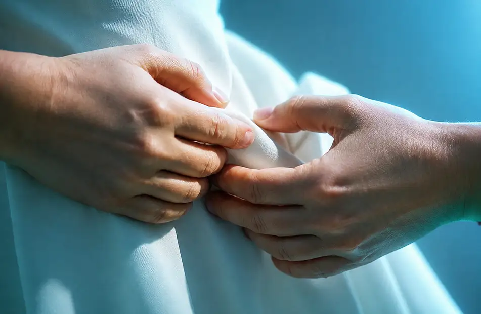Hände prüfen den Stoff eines Kleides vor der Reinigung